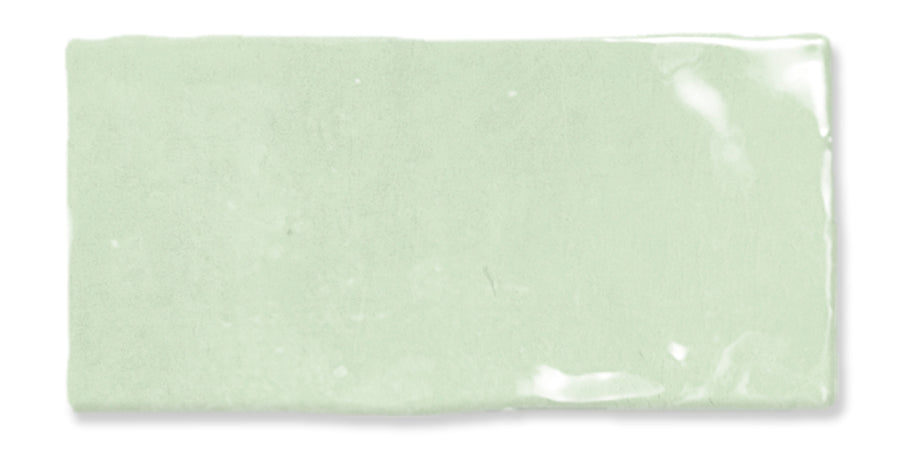 A rectangular, glossy, pale green ceramic tile with slightly uneven edges and a smooth surface reflecting light.