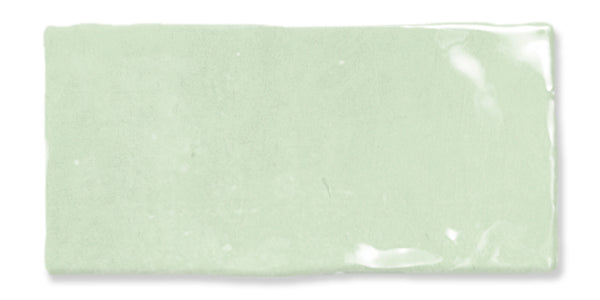 A rectangular, glossy, pale green ceramic tile with slightly uneven edges and a smooth surface reflecting light.