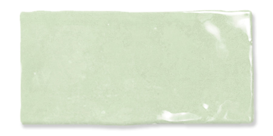 A single rectangular light green ceramic tile with a glossy, slightly uneven surface and visible shine in one corner.