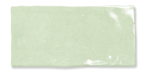 A single rectangular light green ceramic tile with a glossy, slightly uneven surface and visible shine in one corner.