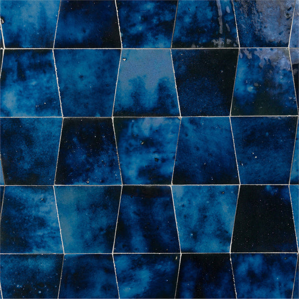 A close-up of the glossy Mistral Trapezoid 3x4 Tile showcases deep blue, irregular polygons with subtle shade variations, producing a textured, geometric surface.