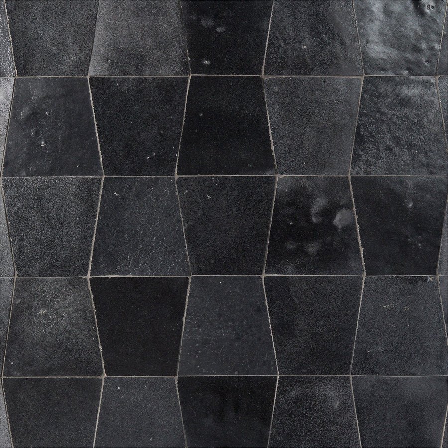 Mistral Trapezoid 3x4 Tile features a black, glossy finish and a unique distorted hexagon shape, creating an elegant, three-dimensional effect with dynamic shades of black and dark gray when arranged in a repeating pattern.