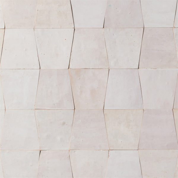 A wall of light beige, hexagonal tiles forms a geometric and textured surface using the elegant Mistral Trapezoid 3x4 Tile.
