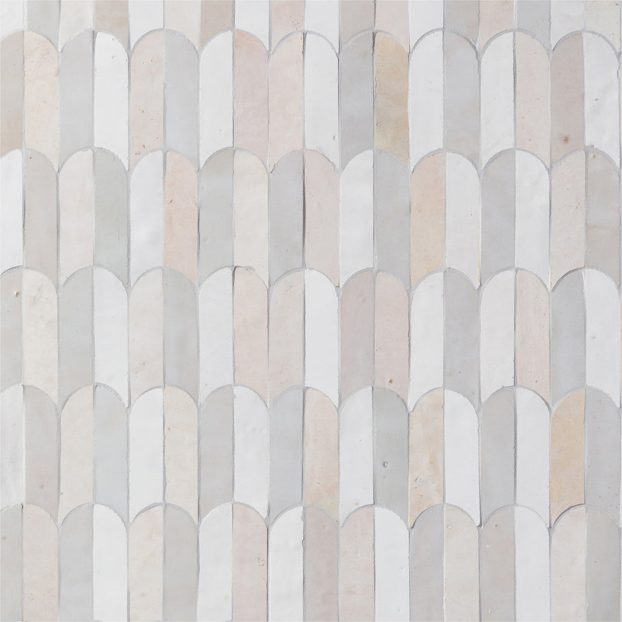 The Mistral Bab Mosaic features a repeating scallop pattern of curved tiles in an exclusive blend of white, cream, and pale gray, bringing artistic elegance to any space.