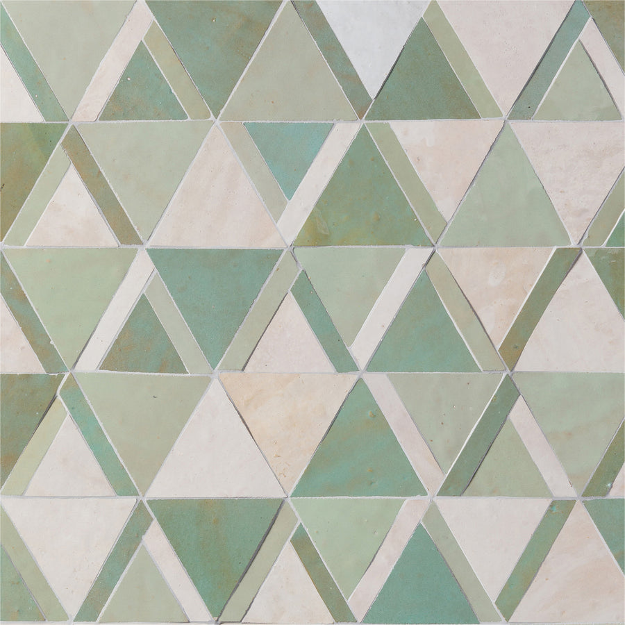 The Mistral Kilim Mosaic features a geometric pattern of green and off-white triangles in a repeating mosaic, creating a symmetrical and visually textured luxury piece.