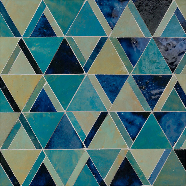 The Mistral Kilim Mosaic features blue, teal, and green triangles in a geometric pattern, forming interlocking rows for a visually striking, repeating design with varied shades and textures.