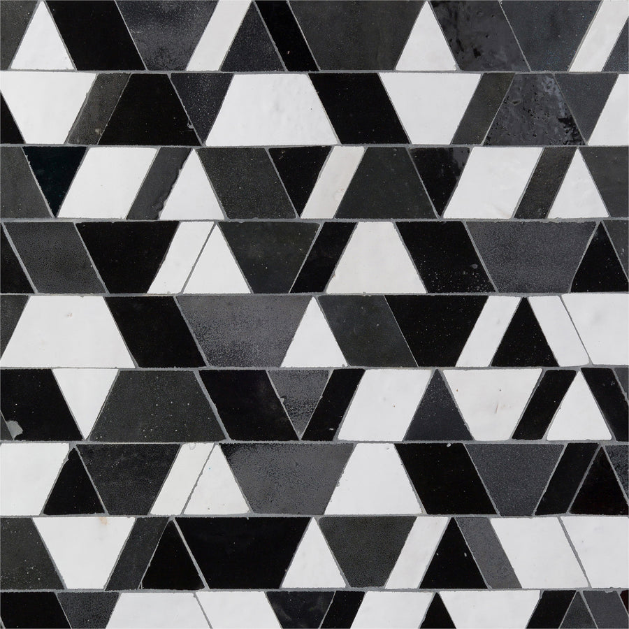 The Mistral Reverie Mosaic features a striking geometric pattern of black, white, and gray triangles in horizontal rows, creating an elegant tile effect that brings exclusive style to any interior.