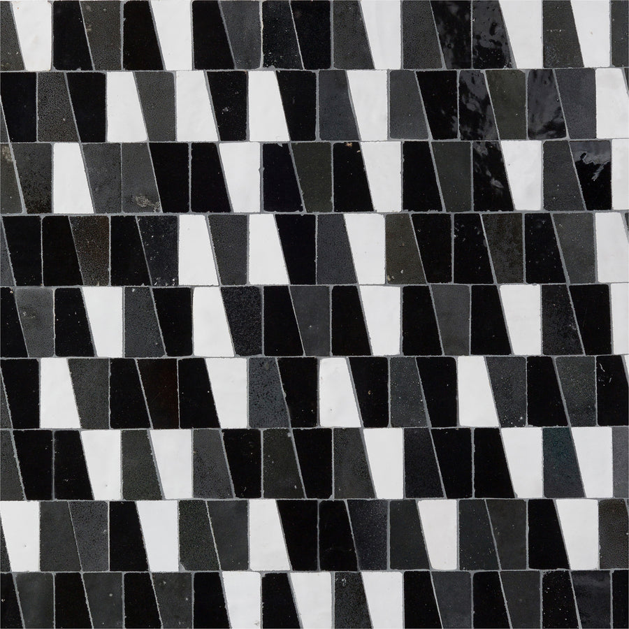 The Mistral Trapezium Mosaic features small rectangular tiles in alternating black, white, and gray shades, forming a dynamic zigzag pattern—an impressive option for elegant home decor or luxury mosaic accents.