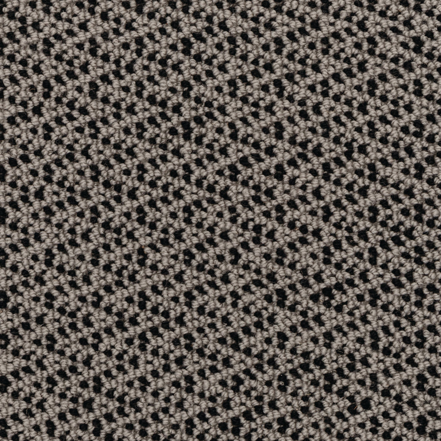 Close-up of the Fretwork On Trend Carpet in Modeled Stone, featuring a textured fabric with a repeating small, diamond-like geometric pattern in beige and black, creating a woven look that suggests durable construction.