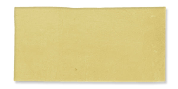 A single, rectangular sheet of uncooked yellow lasagna pasta against a white background.