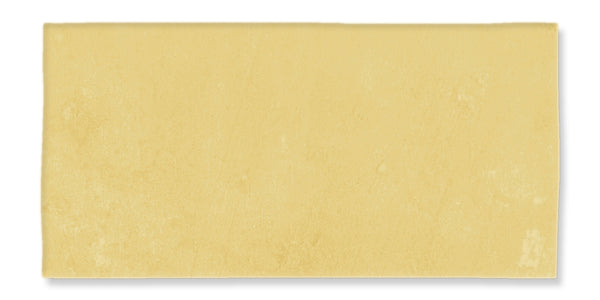 A rectangular sheet of light-yellow pasta dough, smooth and flat, against a white background.