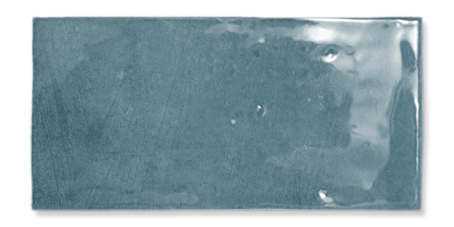 A single rectangular, glossy blue ceramic tile with a slightly uneven surface and subtle reflections.