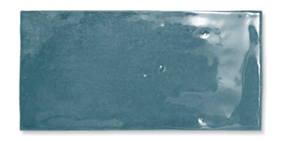 A rectangular, glossy blue ceramic tile with a slightly uneven surface and subtle variations in color.