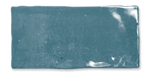 A rectangular teal ceramic tile with a glossy, reflective surface and slightly uneven edges, set against a white background.