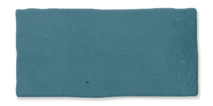 A single rectangular ceramic tile in a muted blue color with slightly uneven edges and a matte, textured surface.