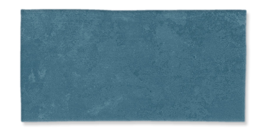 A rectangular blue textured surface, resembling a tile or a piece of fabric, with slightly uneven coloring and edges, set against a white background.