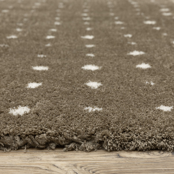 Close-up of a brown, shaggy rug with a soft texture, featuring small white polka dot patterns, placed on a light wooden floor.