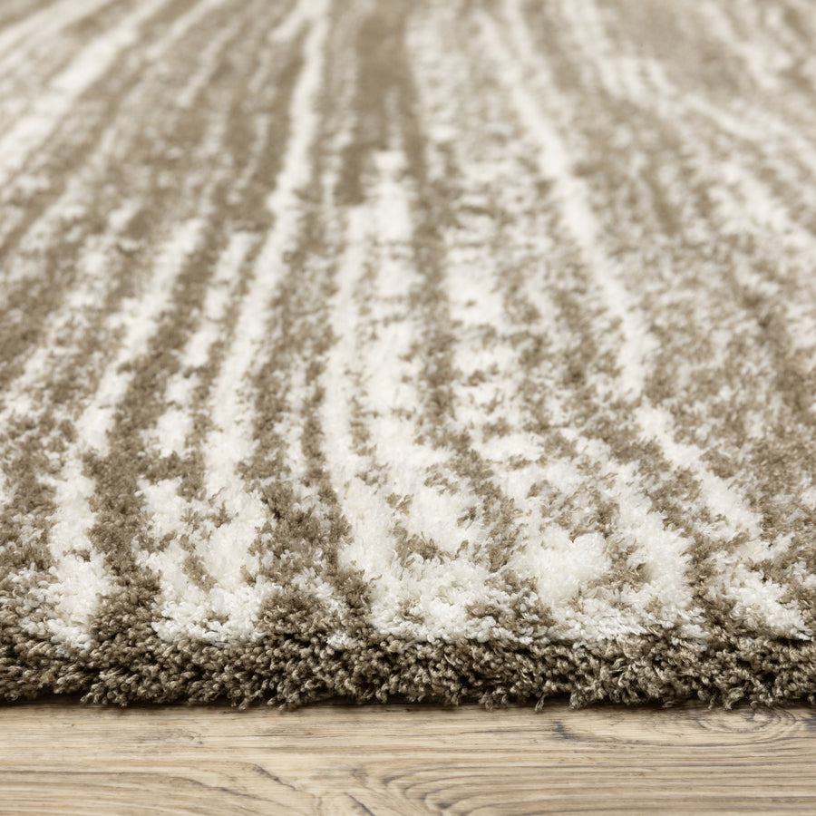 Close-up of a beige and white shaggy rug with a textured, wavy striped pattern, placed on a light wooden floor.