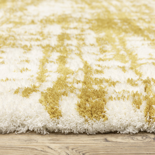 Close-up of a plush area rug with a soft, shaggy texture featuring a white base and abstract yellow pattern, placed on a wooden floor.