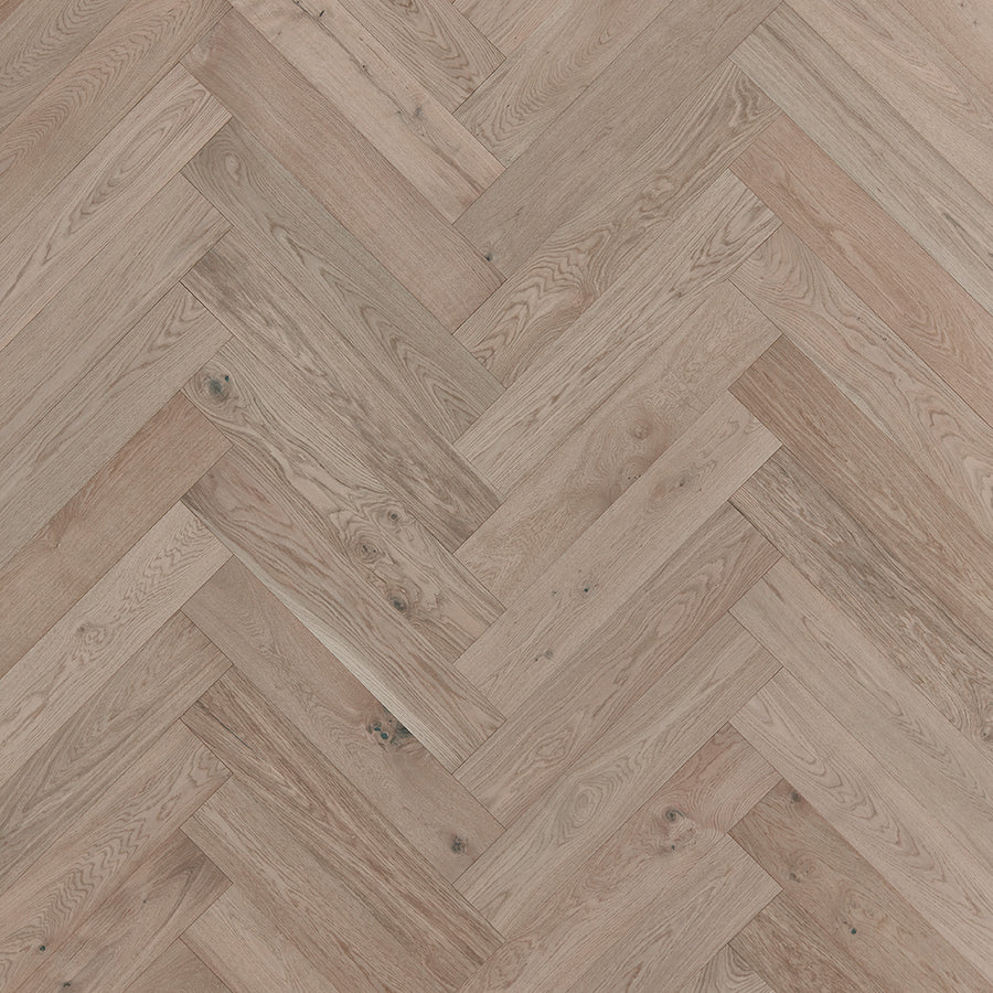 Close-up view of Main Street Herringbone White Oak Hardwood flooring, showcasing its luxurious herringbone pattern, natural wood grain, and elegant light brown tones.