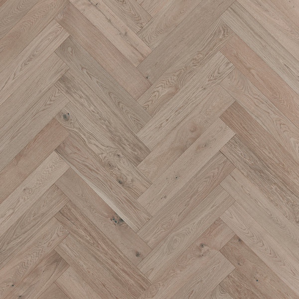 Close-up view of Main Street Herringbone White Oak Hardwood flooring, showcasing its luxurious herringbone pattern, natural wood grain, and elegant light brown tones.