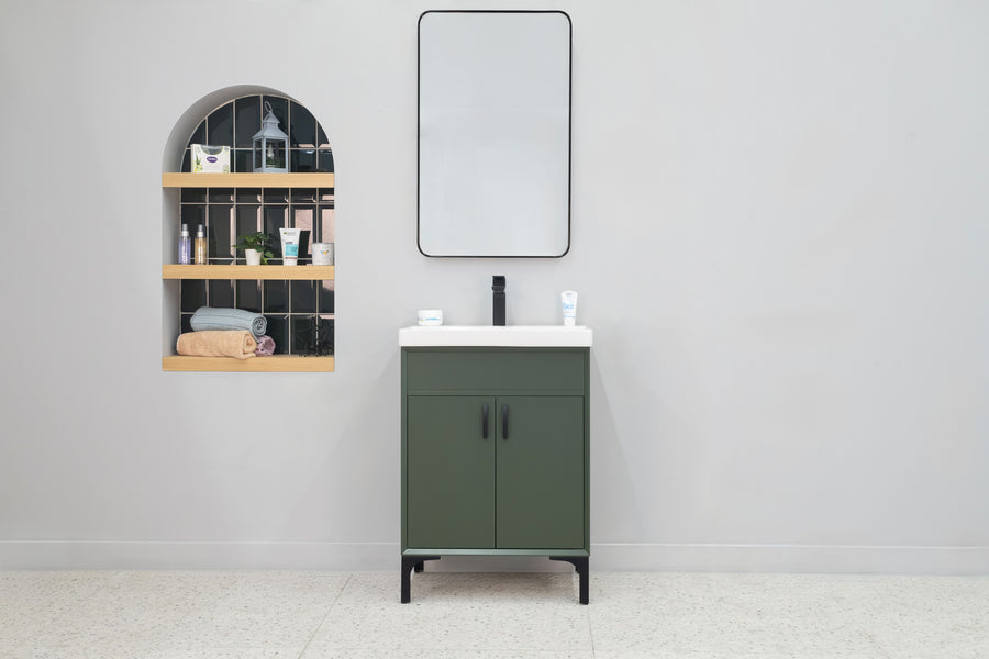 A modern bathroom features the Sempre 24" Vanity with a green finish, white countertop, rectangular mirror, and an arched wall shelf displaying toiletries, towels, and decor against a light gray wall.