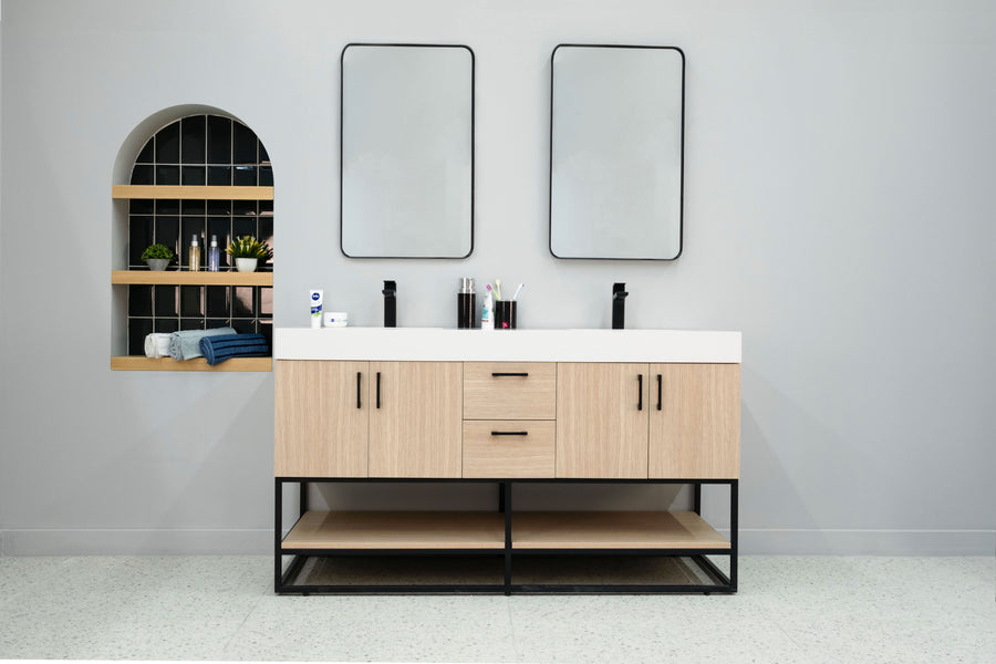 The Solana 60" Double Bowl Vanity features light wood cabinets, black faucets, two rectangular mirrors, and countertop toiletries. A built-in shelf on the left holds towels and personal care items.