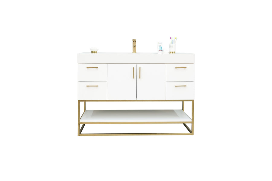 A modern white bathroom vanity with gold accents, four drawers, two center cabinet doors, an open lower shelf, and a countertop with a sink, faucet, soap dish, cup, and toothbrush holder.