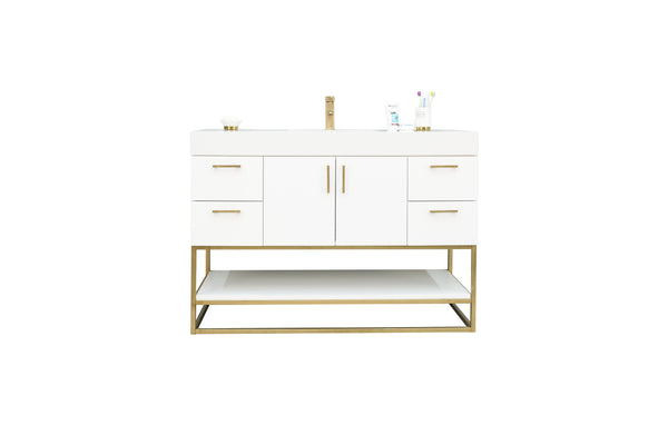 A modern white bathroom vanity with gold accents, four drawers, two center cabinet doors, an open lower shelf, and a countertop with a sink, faucet, soap dish, cup, and toothbrush holder.