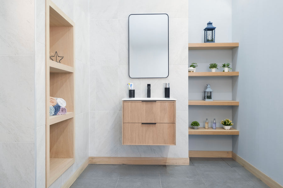 Modern bathroom with the Sorrento 24" Vanity, soft-close drawers, light wood shelves, a rectangular mirror, small plants, and decor arranged against white and gray tiled walls.