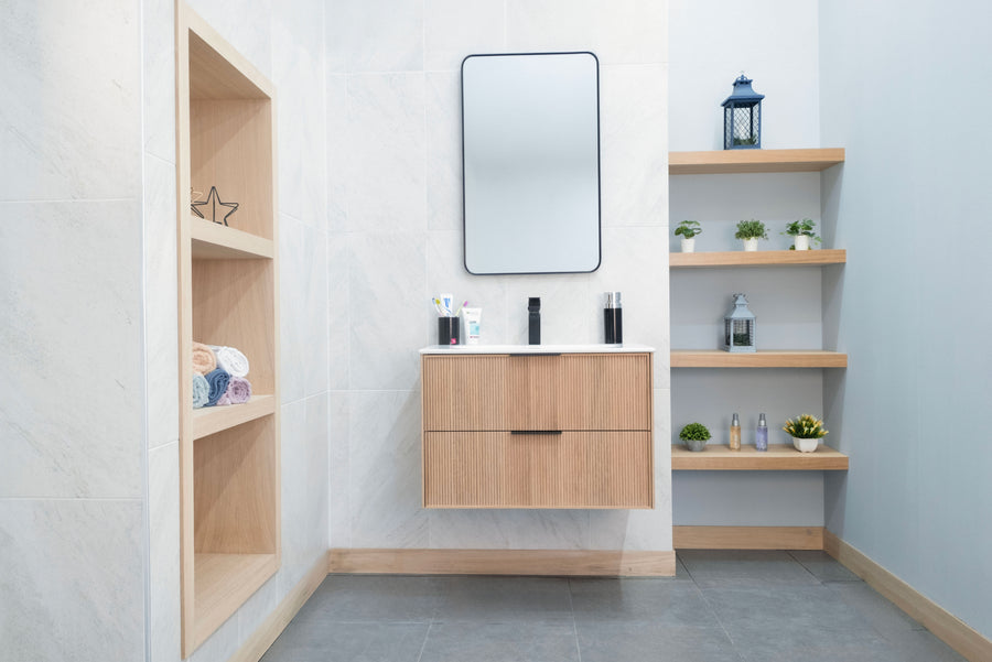 Modern bathroom with white walls, a Sorrento 30" Vanity with soft close drawers, mirror above, built-in shelving for towels, and open shelves displaying small plants and toiletries.