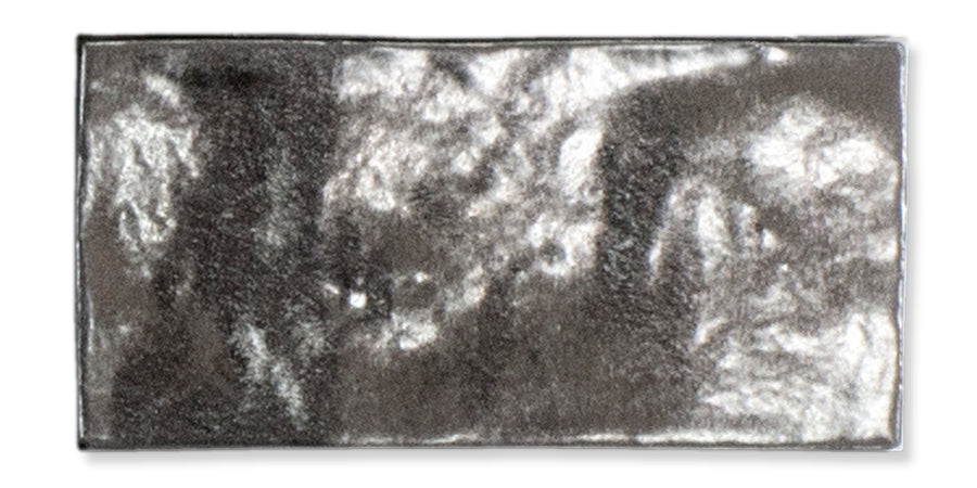 A shiny, rectangular silver-colored metal ingot with a reflective surface and slightly uneven texture, set against a white background.