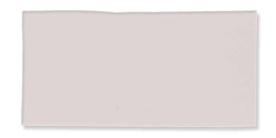 A rectangular, off-white ceramic tile with a slightly uneven top edge and a smooth surface.
