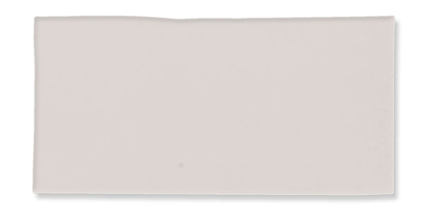 A rectangular, off-white ceramic tile with a slightly uneven top edge and a smooth surface.