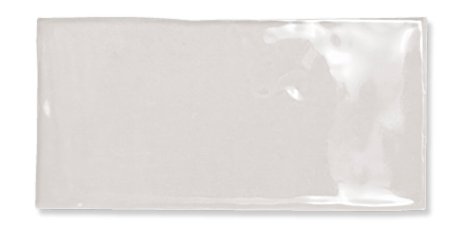 A single glossy, rectangular white ceramic tile with slightly uneven edges and a smooth, shiny surface, photographed against a white background.