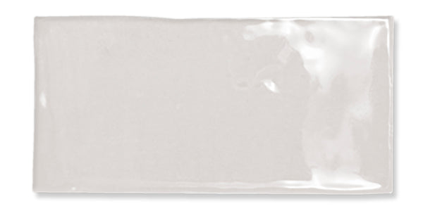 A single glossy, rectangular white ceramic tile with slightly uneven edges and a smooth, shiny surface, photographed against a white background.