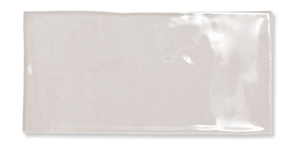 A single, rectangular, glossy light gray ceramic tile with a smooth surface and slightly uneven edges, positioned against a white background.