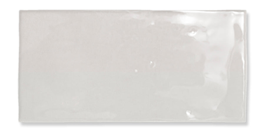 A single rectangular glossy white ceramic tile with slightly uneven surface texture and softly rounded edges, displayed against a white background.