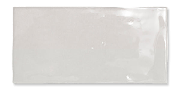 A single rectangular glossy white ceramic tile with slightly uneven surface texture and softly rounded edges, displayed against a white background.