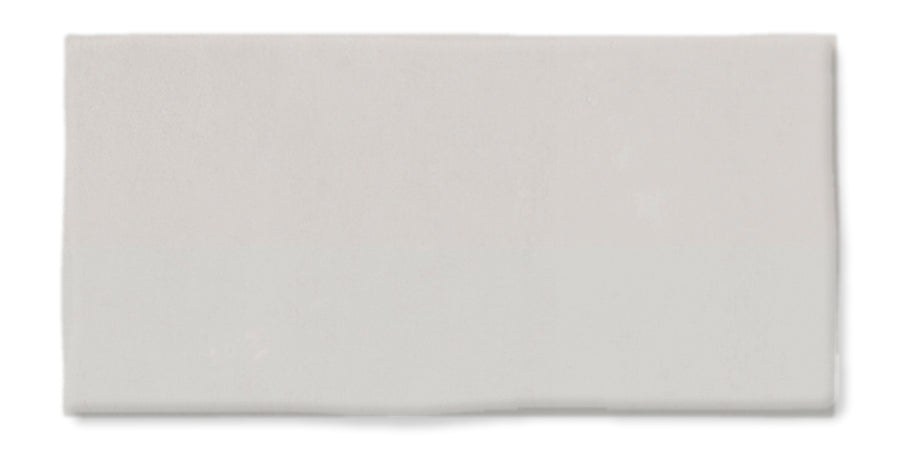 A rectangular, plain white ceramic tile with a smooth, glossy surface and slightly uneven edges displayed against a white background.