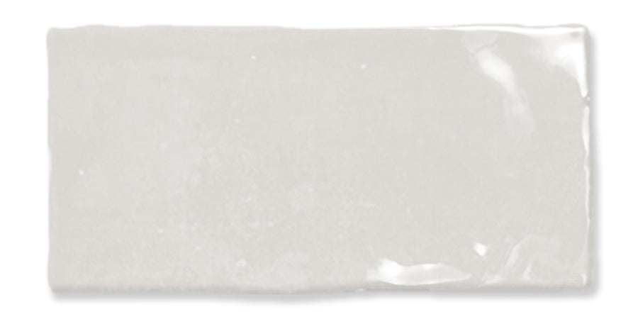 A rectangular, glossy white ceramic tile with slightly uneven edges, reflecting light on its smooth surface.