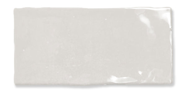 A rectangular, glossy white ceramic tile with slightly uneven edges, reflecting light on its smooth surface.