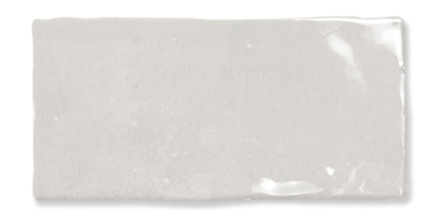 A rectangular, glossy white ceramic tile with slightly uneven edges and a subtle reflective surface.