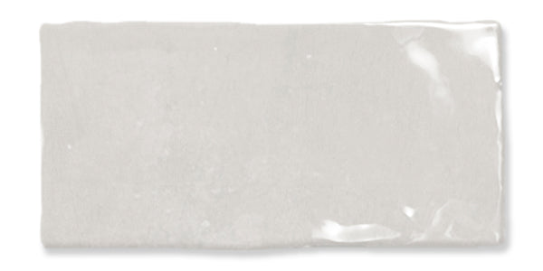 A rectangular, glossy white ceramic tile with slightly uneven edges and a subtle reflective surface.
