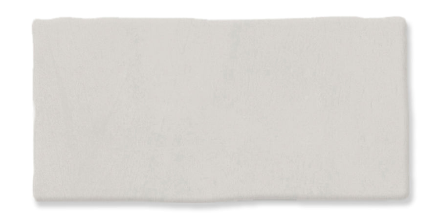 A rectangular piece of clay or dough, light gray in color, with slightly uneven edges and a smooth, matte surface on a white background.