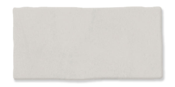 A rectangular piece of clay or dough, light gray in color, with slightly uneven edges and a smooth, matte surface on a white background.
