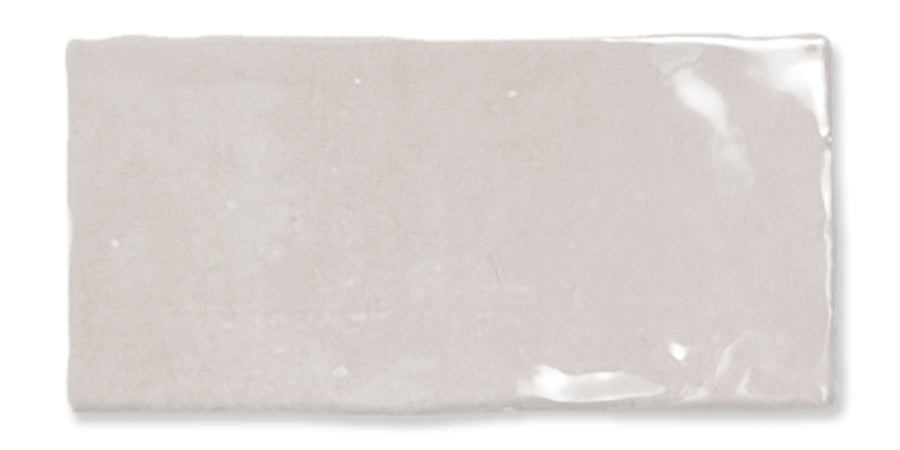 A rectangular, glossy light gray ceramic tile with slightly uneven edges and a smooth, reflective surface.