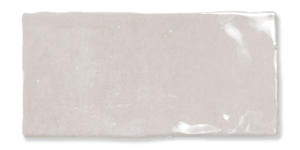 A rectangular, glossy light gray ceramic tile with slightly uneven edges and a smooth, reflective surface.