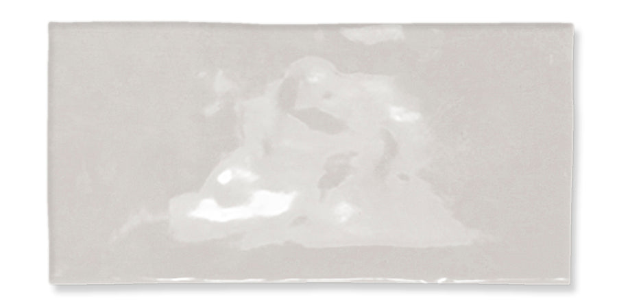 A glossy, rectangular, off-white ceramic tile with a slightly uneven surface and subtle reflections.