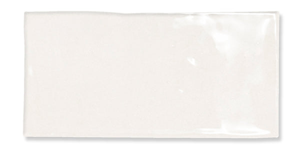 A rectangular, glossy white tile with a smooth surface and slightly uneven edges, reflecting light on its top right corner.